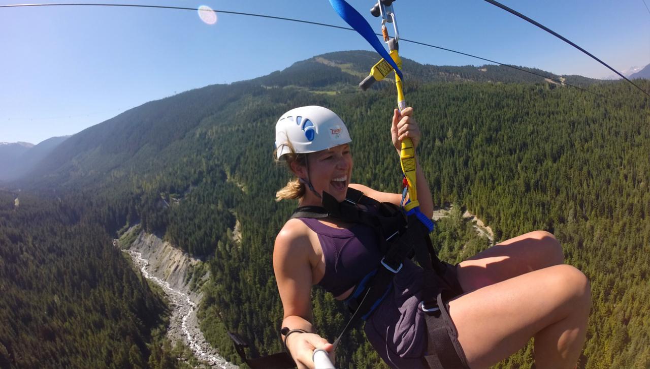 Whistler in the summer: woman zip-lining through the forest.