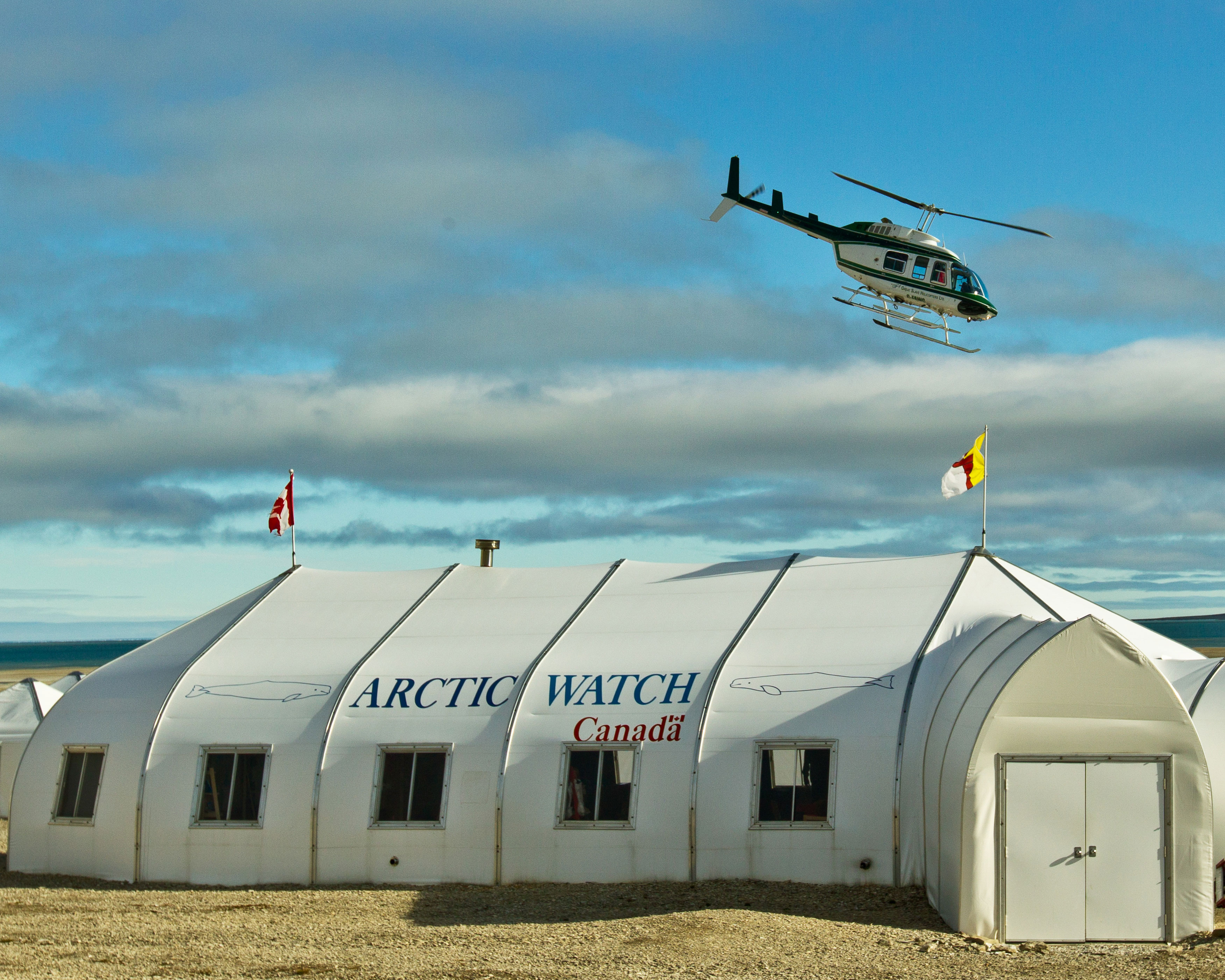 Finest lodges: white lodge in the Arctic with a helicopter flying overhead.