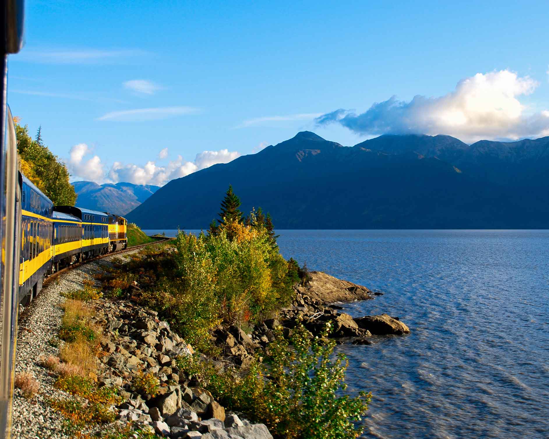High-end train travel: Alaskan train going past lakes and mountains.