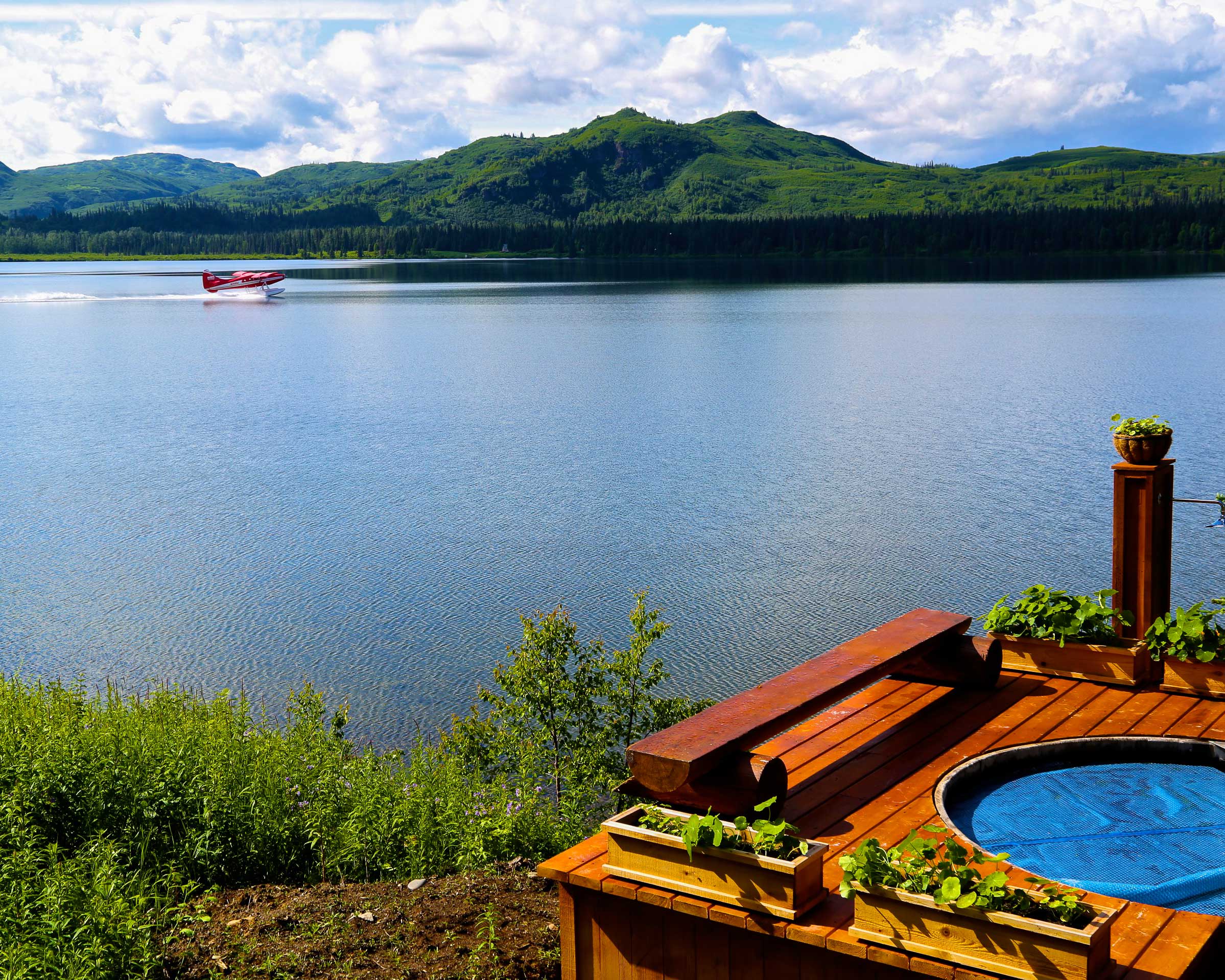 Finest lodges: hot tub in front of a lake with a float plane going by.