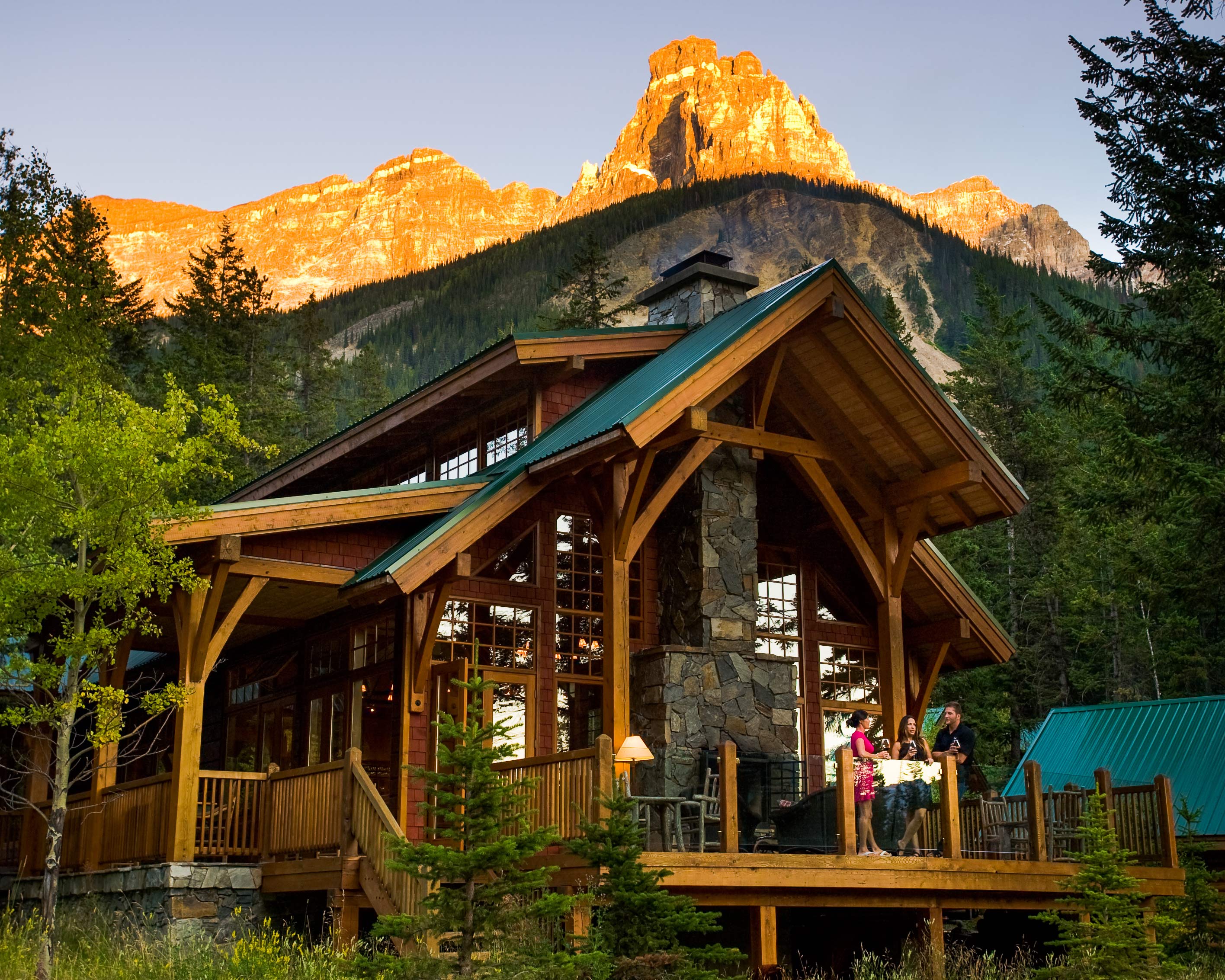 Honeymoon destinations in Canada: a luxury lodge in front of mountains at sunset. 
