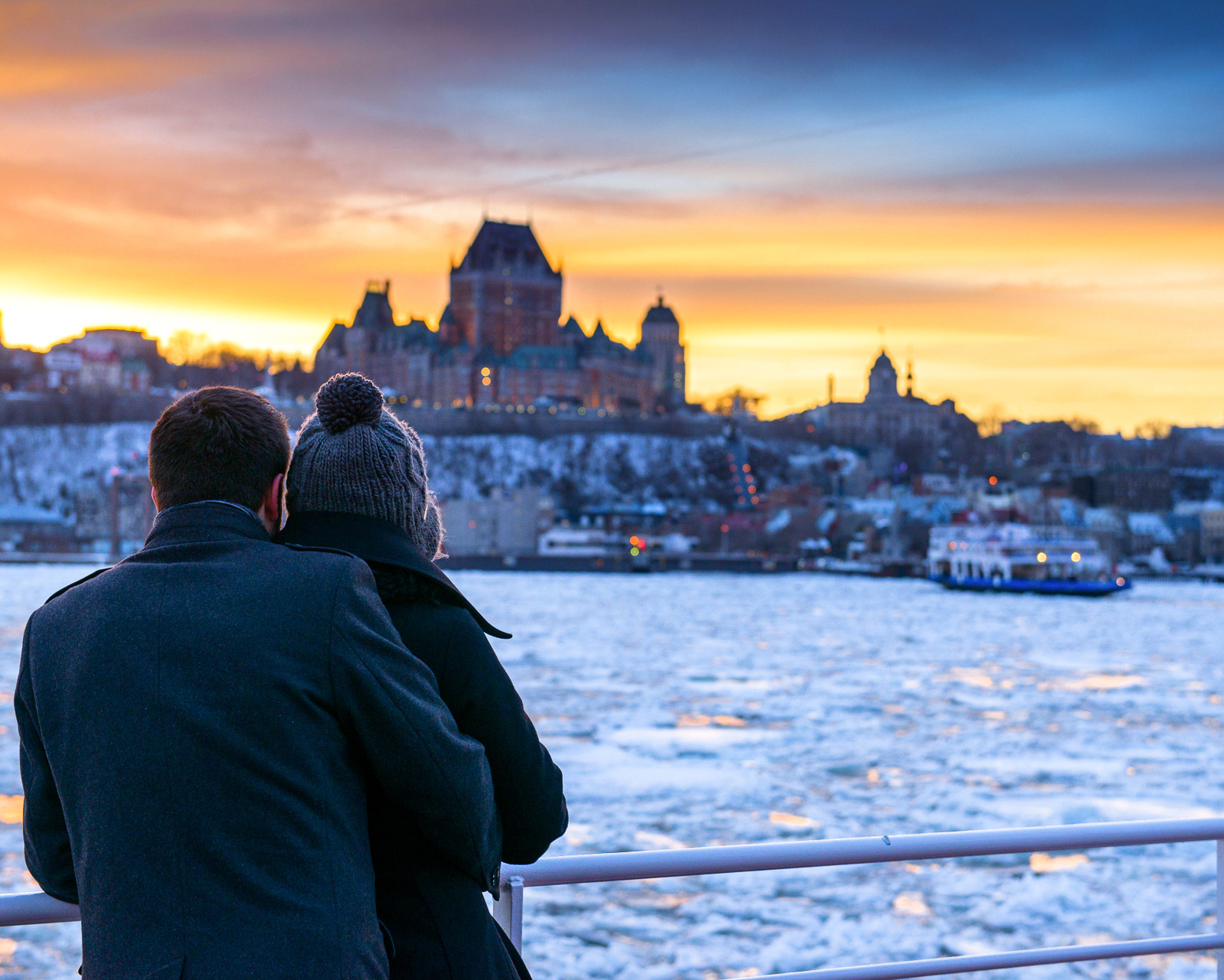 Honeymoon destinations in Canada: couple looks over frozen river at Quebec City. 