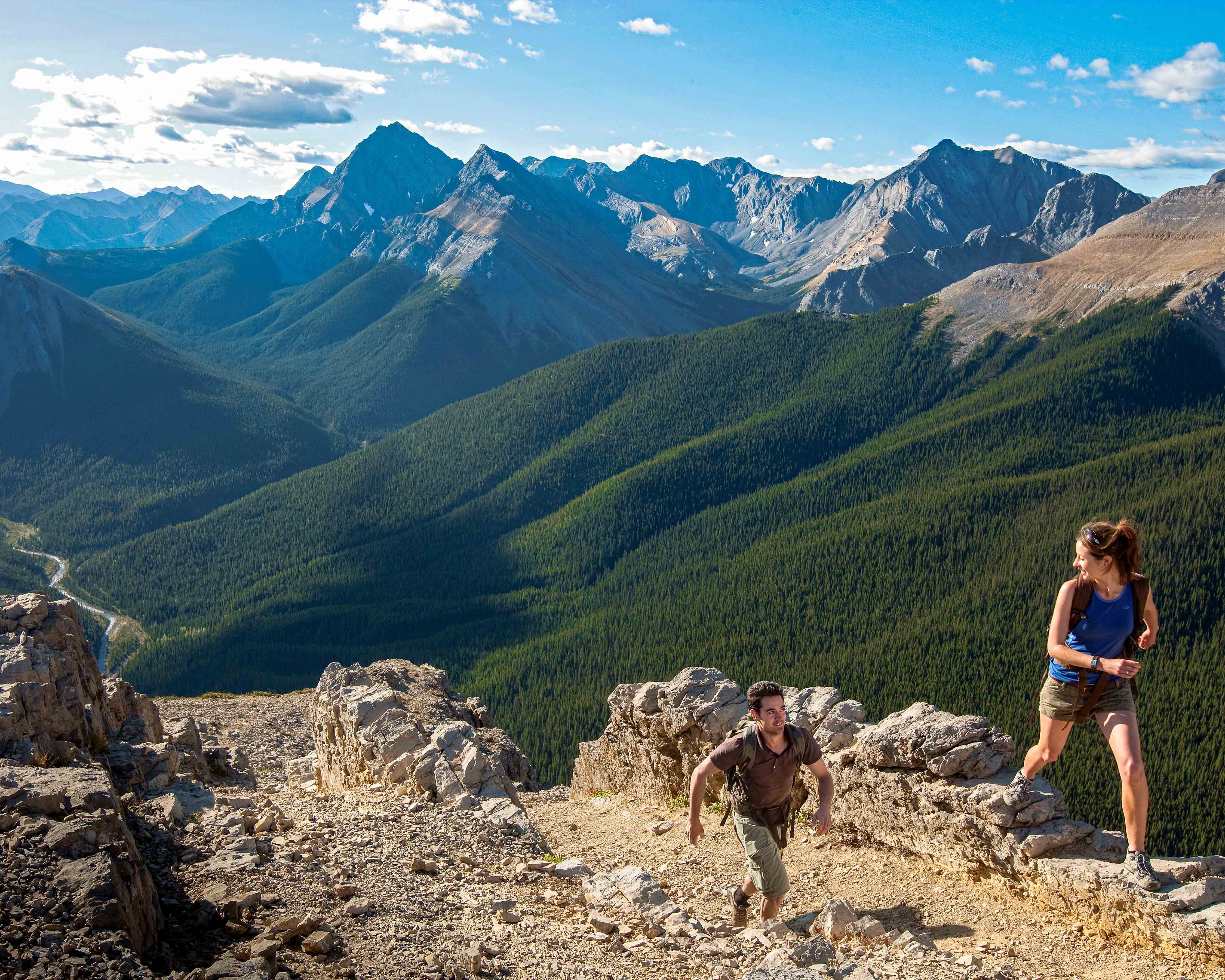 Honeymoon destinations in Canada: young couple running with mountains in background.